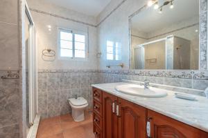 a bathroom with a sink and a toilet and a mirror at Chalet andaluz Los Alberos in Coín +18 photos