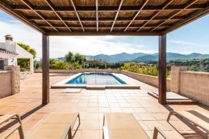 an outdoor patio with a pool and views of the mountains at Chalet andaluz Los Alberos in Coín