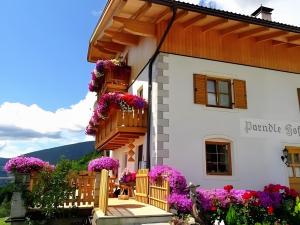 a woman sitting on the porch of a house with flowers at Parndlehof in Villandro