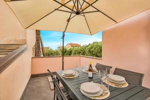 a table with an umbrella and a table with wine glasses at Dal Pernè in Volastra +5 photos