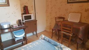 a living room with a table and a desk with a microwave at Villa Eugénie in La Bourboule