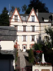 a large white house with a courtyard in front of it at Villa Eugénie in La Bourboule