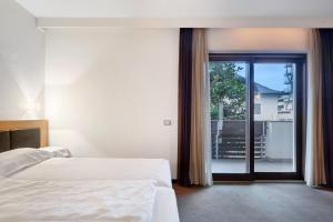 a hotel room with a bed and a large window at Residence Alpenrose in Col di Villa