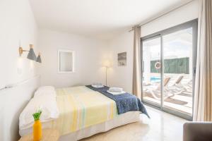 a white bedroom with a bed and a balcony at Villa Sam 3 in Can Picafort +16 photos