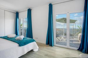 a bedroom with a bed with blue curtains and a balcony at Casa Do Tempo com Jacuzzi in Ribeira Brava