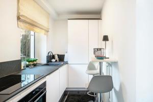 a kitchen with white cabinets and a sink and a chair at Ferienwohnung Aachen Süd in Aachen +9 photos