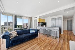 a living room with a blue couch and a kitchen at Adelaide Central Skyline Panoramic Suite Three in Adelaide