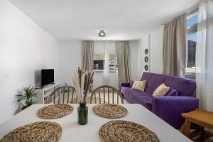 a living room with two tables and a purple couch at Jimaguas in Tamaduste