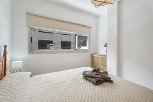 a white bedroom with a bed with a window at Jimaguas in Tamaduste