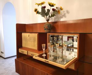 a display case with glasses and a vase with flowers at Spacious Historic Apartment F1 in Gravedona