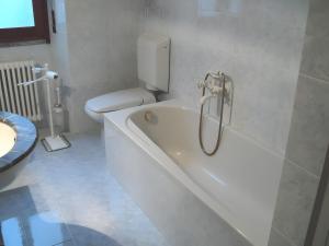 a white bathroom with a tub and a toilet at Spacious Historic Apartment F1 in Gravedona