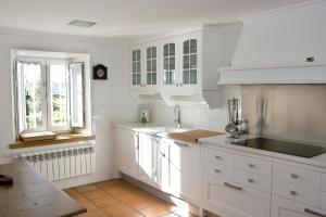 a white kitchen with white cabinets and a window at Casa del Lago de Campoo in Orzales +23 photos