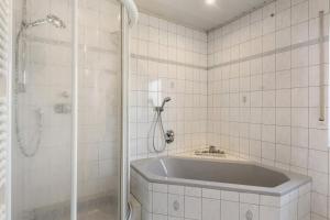 a white tiled bathroom with a tub and a shower at Wohung zum Ausblick in Plettenberg +17 photos