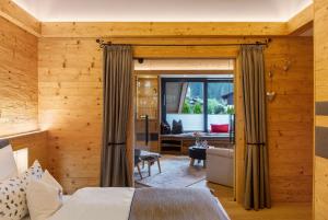 a bedroom with wooden walls and a large window at Alpenchalet 19 in Krün