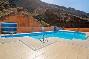 a swimming pool with a mountain in the background at Paraiso Playa Taurito in Taurito