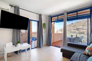 a living room with a couch and a large window at Paraiso Playa Taurito in Taurito