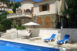 a house with two chairs and an umbrella next to a pool at Casa Terra de Chispa by Easy Brava in Calonge