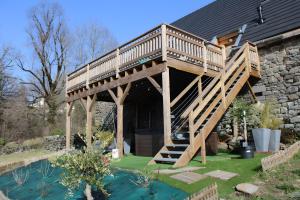 a wooden deck on a house with a swimming pool at Gite La Grange De Loey in Méallet