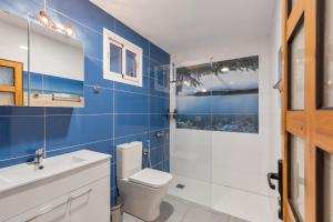 a bathroom with a white toilet and a blue wall at Casa Ñico in Artenara +19 photos