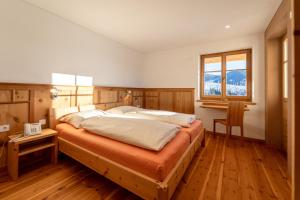 a bedroom with a large bed with wooden floors and a window at Lexn Radein in Redagno +37 photos