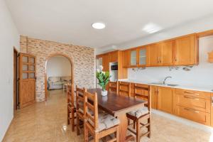 a kitchen with wooden cabinets and a table and chairs at Casa Ñico in Artenara