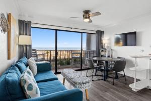 a living room with a blue couch and a table at Boardwalk Breeze Oceanfront Pool Villa in Carolina Beach