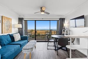 a living room with a blue couch and a table at Boardwalk Breeze Oceanfront Pool Villa in Carolina Beach
