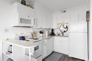 a white kitchen with white cabinets and a white refrigerator at Boardwalk Breeze Oceanfront Pool Villa in Carolina Beach