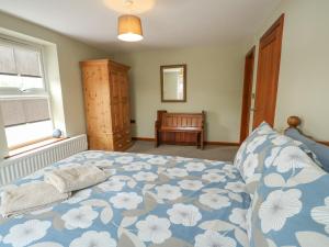 a bedroom with a blue and white bed with a window at Chapel House in Llantrisant