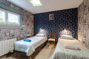 a bedroom with two beds and a chair at Gîte Lavand Cottage À Brantôme in Brantôme
