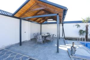 a patio with a table and chairs and a roof at Forest Luxe A-Frame Villa in Quba