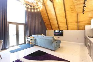 a living room with a blue couch and wooden ceilings at Forest Luxe A-Frame Villa in Quba