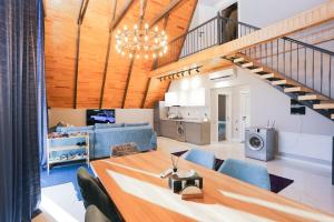 a living room with a wooden table and blue chairs at Forest Luxe A-Frame Villa in Quba