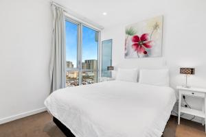 a white bedroom with a large bed and a window at Adelaide Central Skyline Panoramic Suite Three in Adelaide
