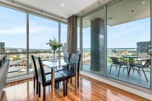 a dining room with a table and chairs and large windows at Adelaide Central Skyline Panoramic Suite Three in Adelaide