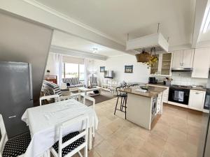 a kitchen with white cabinets and a table and chairs at LaMer No 5 in Stilbaai