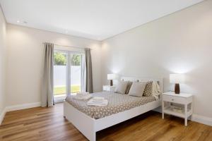 a white bedroom with a bed and a window at Casa D'Avó - Family Coastal Escape in Casa Nova