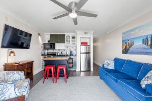 a living room with a blue couch and red stools at CB Boardwalk Condo Oceanfront Pool Villa in Carolina Beach