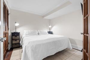 a white bedroom with a white bed and two lamps at CB Boardwalk Condo Oceanfront Pool Villa in Carolina Beach