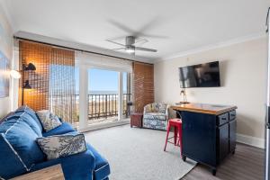 a living room with a blue couch and a desk at CB Boardwalk Condo Oceanfront Pool Villa in Carolina Beach