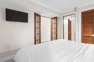 a bedroom with a white bed with a flat screen tv at CB Boardwalk Condo Oceanfront Pool Villa in Carolina Beach