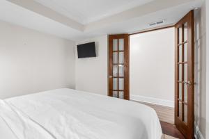 a white bedroom with a bed and a television at CB Boardwalk Condo Oceanfront Pool Villa in Carolina Beach +30 photos