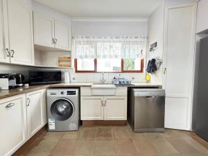 a kitchen with white cabinets and a sink and a dishwasher at LaMer No 5 in Stilbaai