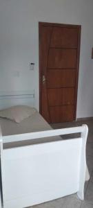 a bedroom with a bed and a wooden door at Apartamento de frente ao mar - Centro in Peruíbe