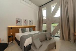 a bedroom with a bed and a couch and a window at Heritage X in São Paulo