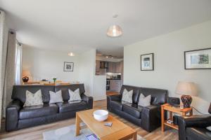 a living room with black leather couches and a table at 3 Combehaven in Salcombe