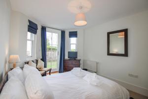 a bedroom with a white bed and a television at 3 Combehaven in Salcombe