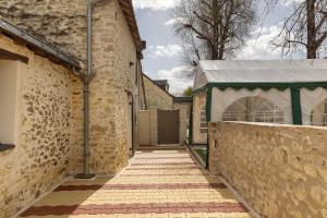 a brick alley with a gate and a building at Petit gîte bleu jusqu'à 4 personnes in Huillé