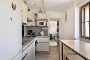 a kitchen with white cabinets and a wooden counter top at Petit gîte bleu jusqu'à 4 personnes in Huillé +16 photos