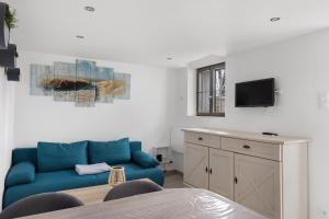 a living room with a blue couch and a tv at Petit gîte bleu jusqu'à 4 personnes in Huillé